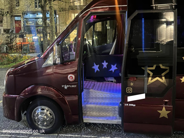Party bus with passenger door open and interior lights on display